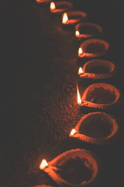 Happy Diwali - many Terracotta diya or oil lamps arranged over clay surface or ground in one line or curved or zigzag form, selective focus — Stock Photo, Image
