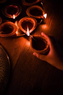Mutlu bayramlar - holding veya aydınlatma veya pirinç levha, seçici odak diwali diya veya kil Lambada düzenlenmesi el