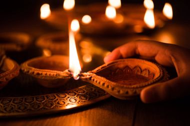 Mutlu bayramlar - holding veya aydınlatma veya pirinç levha, seçici odak diwali diya veya kil Lambada düzenlenmesi el