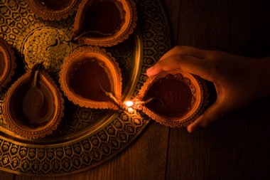 Mutlu bayramlar - holding veya aydınlatma veya pirinç levha, seçici odak diwali diya veya kil Lambada düzenlenmesi el
