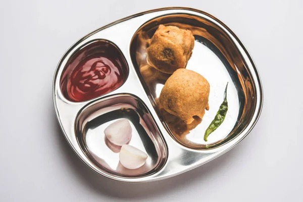 Aloo Bonda, Batata Vada ou Alubonda - malbouffe indienne frite mais plats savoureux ou en-cas servis dans une assiette en acier inoxydable sur fond blanc avec ketchup à la tomate et friture verte froide, accent sélectif — Photo