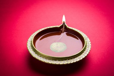 Büyük ışıklı tasarımcı diwali diya veya kil lamba yerleştirilmiş kırmızı arka plan, moody aydınlatma, seçici odak üzerinde