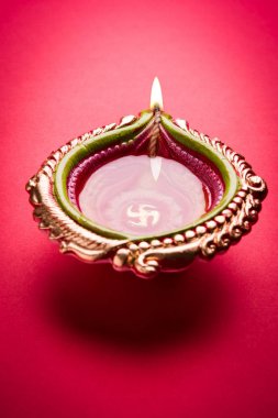 Büyük ışıklı tasarımcı diwali diya veya kil lamba yerleştirilmiş kırmızı arka plan, moody aydınlatma, seçici odak üzerinde