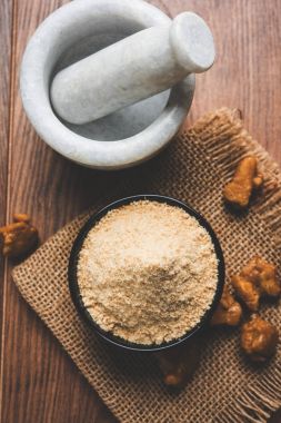 Şeytantersi kek ve toz veya Hing veya Hint yemek tarifleri ile büyük tahta kaşık ve harç, seçici odak önemli bir madde olan Heeng