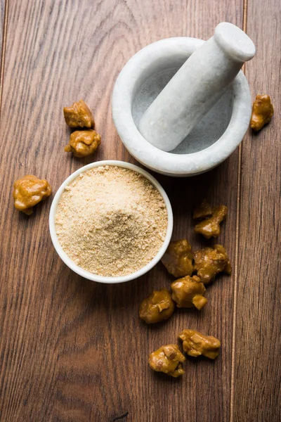 Şeytantersi kek ve toz veya Hing veya Hint yemek tarifleri ile büyük tahta kaşık ve harç, seçici odak önemli bir madde olan Heeng