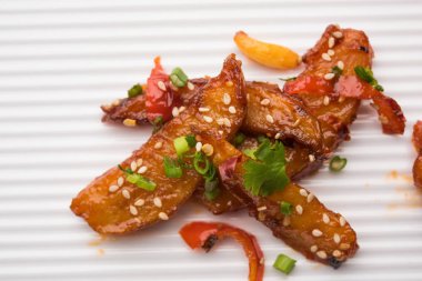 Tatlım kırmızı biber patates veya patates dilimleri, popüler Hint-Çin başlangıç tarifi, susam ve soğan ile süslenmiş. seçici odak