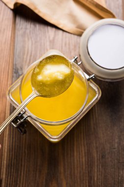 Desi Ghee veya cam veya bakır kapsayıcı veya kaşık, seçici odak ile seramik kavanoz içinde eritilmiş tereyağı