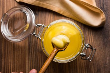 Desi Ghee veya cam veya bakır kapsayıcı veya kaşık, seçici odak ile seramik kavanoz içinde eritilmiş tereyağı