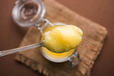 Desi Ghee veya cam veya bakır kapsayıcı veya kaşık, seçici odak ile seramik kavanoz içinde eritilmiş tereyağı