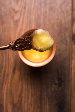 Desi Ghee veya cam veya bakır kapsayıcı veya kaşık, seçici odak ile seramik kavanoz içinde eritilmiş tereyağı