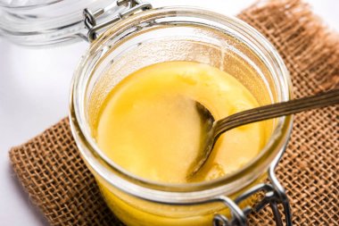Desi Ghee veya cam veya bakır kapsayıcı veya kaşık, seçici odak ile seramik kavanoz içinde eritilmiş tereyağı