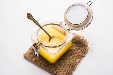 Desi Ghee veya cam veya bakır kapsayıcı veya kaşık, seçici odak ile seramik kavanoz içinde eritilmiş tereyağı