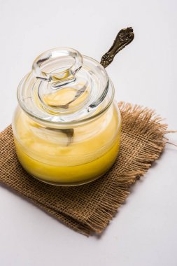 Desi Ghee veya cam veya bakır kapsayıcı veya kaşık, seçici odak ile seramik kavanoz içinde eritilmiş tereyağı