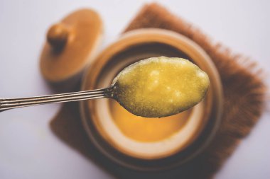 Desi Ghee veya cam veya bakır kapsayıcı veya kaşık, seçici odak ile seramik kavanoz içinde eritilmiş tereyağı