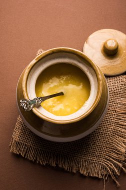Desi Ghee veya cam veya bakır kapsayıcı veya kaşık, seçici odak ile seramik kavanoz içinde eritilmiş tereyağı