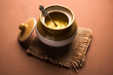 Desi Ghee veya cam veya bakır kapsayıcı veya kaşık, seçici odak ile seramik kavanoz içinde eritilmiş tereyağı