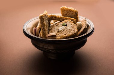 Gajak or til papdi or patti is a dry sweet cake - made of sesame seeds, ground nuts and jaggery, consumed in indian winter especially during Makar Sankranti festival on 14th january clipart