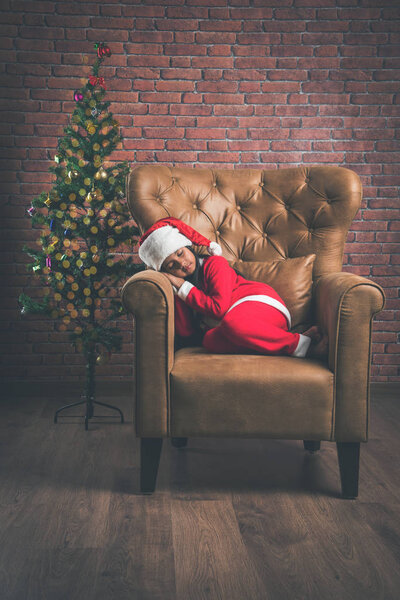 Cute Little Indian or Asian Girl sleeping on chair while waiting for Santa Claus on Christmas night