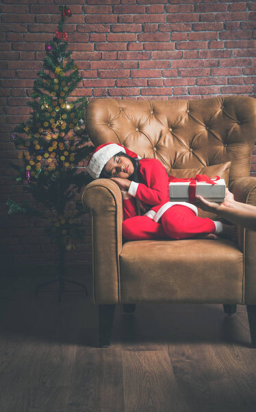 Cute Little Indian or Asian Girl sleeping on chair while waiting for Santa Claus on Christmas night