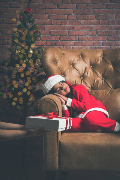 Cute Little Indian or Asian Girl sleeping on chair while waiting for Santa Claus on Christmas night