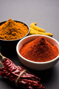 zerdeçal ve kırmızı biber tozu beyaz ya da siyah arka plan üzerinde seramik bir kasede yığını 
