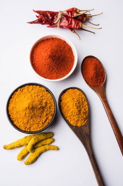 zerdeçal ve kırmızı biber tozu beyaz ya da siyah arka plan üzerinde seramik bir kasede yığını 