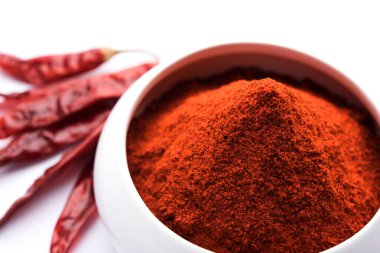 Kırmızı renkli arka plan veya düz arka plan üzerinde kırmızı biber tozu yığını üzerinde kurutulmuş kırmızı biber ile bir kasede Chilly Powder