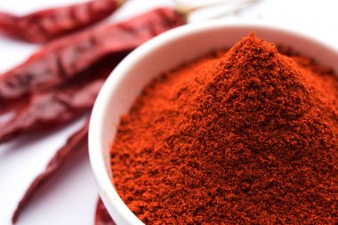 Kırmızı renkli arka plan veya düz arka plan üzerinde kırmızı biber tozu yığını üzerinde kurutulmuş kırmızı biber ile bir kasede Chilly Powder