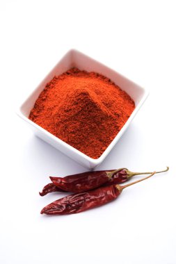 Kırmızı renkli arka plan veya düz arka plan üzerinde kırmızı biber tozu yığını üzerinde kurutulmuş kırmızı biber ile bir kasede Chilly Powder