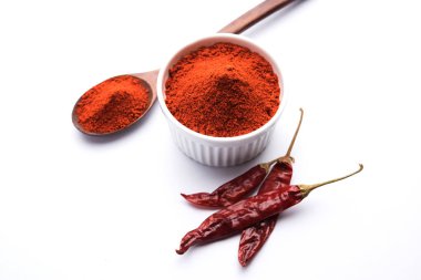Kırmızı renkli arka plan veya düz arka plan üzerinde kırmızı biber tozu yığını üzerinde kurutulmuş kırmızı biber ile bir kasede Chilly Powder
