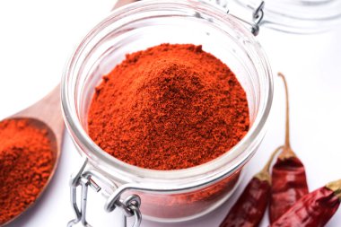 Kırmızı renkli arka plan veya düz arka plan üzerinde kırmızı biber tozu yığını üzerinde kurutulmuş kırmızı biber ile bir kasede Chilly Powder