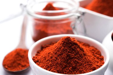 Kırmızı renkli arka plan veya düz arka plan üzerinde kırmızı biber tozu yığını üzerinde kurutulmuş kırmızı biber ile bir kasede Chilly Powder