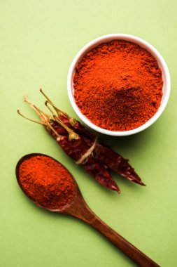 Kırmızı renkli arka plan veya düz arka plan üzerinde kırmızı biber tozu yığını üzerinde kurutulmuş kırmızı biber ile bir kasede Chilly Powder