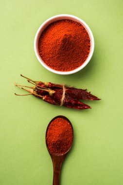 Kırmızı renkli arka plan veya düz arka plan üzerinde kırmızı biber tozu yığını üzerinde kurutulmuş kırmızı biber ile bir kasede Chilly Powder