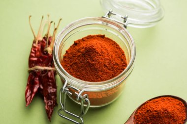 Kırmızı renkli arka plan veya düz arka plan üzerinde kırmızı biber tozu yığını üzerinde kurutulmuş kırmızı biber ile bir kasede Chilly Powder