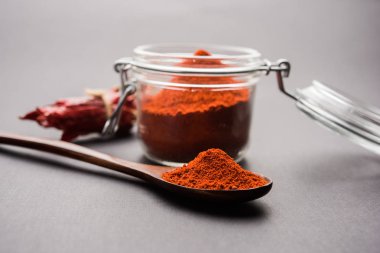 Kırmızı renkli arka plan veya düz arka plan üzerinde kırmızı biber tozu yığını üzerinde kurutulmuş kırmızı biber ile bir kasede Chilly Powder