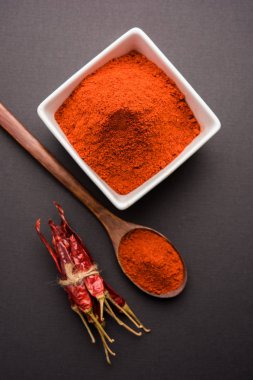 Kırmızı renkli arka plan veya düz arka plan üzerinde kırmızı biber tozu yığını üzerinde kurutulmuş kırmızı biber ile bir kasede Chilly Powder