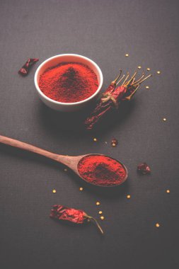 Kırmızı renkli arka plan veya düz arka plan üzerinde kırmızı biber tozu yığını üzerinde kurutulmuş kırmızı biber ile bir kasede Chilly Powder