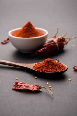 Kırmızı renkli arka plan veya düz arka plan üzerinde kırmızı biber tozu yığını üzerinde kurutulmuş kırmızı biber ile bir kasede Chilly Powder