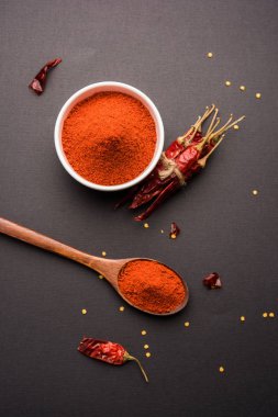 Kırmızı renkli arka plan veya düz arka plan üzerinde kırmızı biber tozu yığını üzerinde kurutulmuş kırmızı biber ile bir kasede Chilly Powder