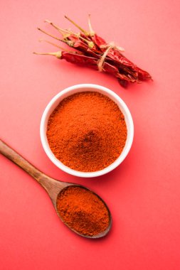 Kırmızı renkli arka plan veya düz arka plan üzerinde kırmızı biber tozu yığını üzerinde kurutulmuş kırmızı biber ile bir kasede Chilly Powder