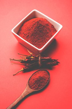 Kırmızı renkli arka plan veya düz arka plan üzerinde kırmızı biber tozu yığını üzerinde kurutulmuş kırmızı biber ile bir kasede Chilly Powder