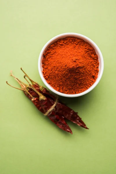 Red Chilly Powder in a bowl with dried red chillies over colourful background or pile of red chilli powder over plain background