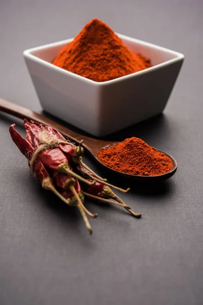 Red Chilly Powder in a bowl with dried red chillies over colourful background or pile of red chilli powder over plain background
