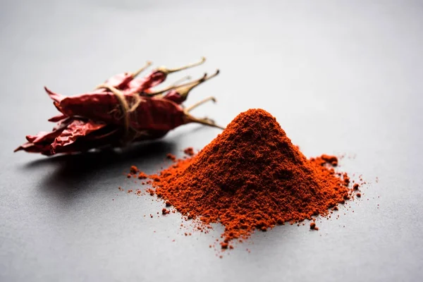 Red Chilly Powder in a bowl with dried red chillies over colourful background or pile of red chilli powder over plain background