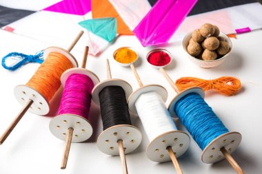 mutlu Makar Sankranti tebrik kartı - Tilgul veya bir kase veya plate haldi Recep ile ve Fikri Reel/Chakri /Spool renkli iplik veya manjha ve düz arka plan üzerinde uçurtma ile çiçeklerle gidecektir Til