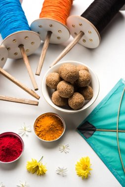 mutlu Makar Sankranti tebrik kartı - Tilgul veya bir kase veya plate haldi Recep ile ve Fikri Reel/Chakri /Spool renkli iplik veya manjha ve düz arka plan üzerinde uçurtma ile çiçeklerle gidecektir Til