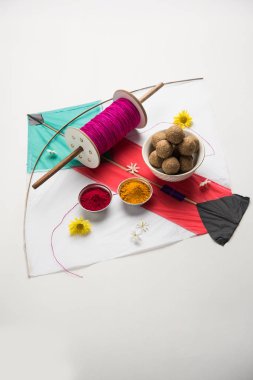 mutlu Makar Sankranti tebrik kartı - Tilgul veya bir kase veya plate haldi Recep ile ve Fikri Reel/Chakri /Spool renkli iplik veya manjha ve düz arka plan üzerinde uçurtma ile çiçeklerle gidecektir Til