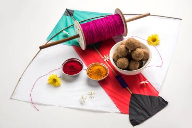 mutlu Makar Sankranti tebrik kartı - Tilgul veya bir kase veya plate haldi Recep ile ve Fikri Reel/Chakri /Spool renkli iplik veya manjha ve düz arka plan üzerinde uçurtma ile çiçeklerle gidecektir Til