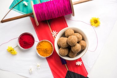 mutlu Makar Sankranti tebrik kartı - Tilgul veya bir kase veya plate haldi Recep ile ve Fikri Reel/Chakri /Spool renkli iplik veya manjha ve düz arka plan üzerinde uçurtma ile çiçeklerle gidecektir Til